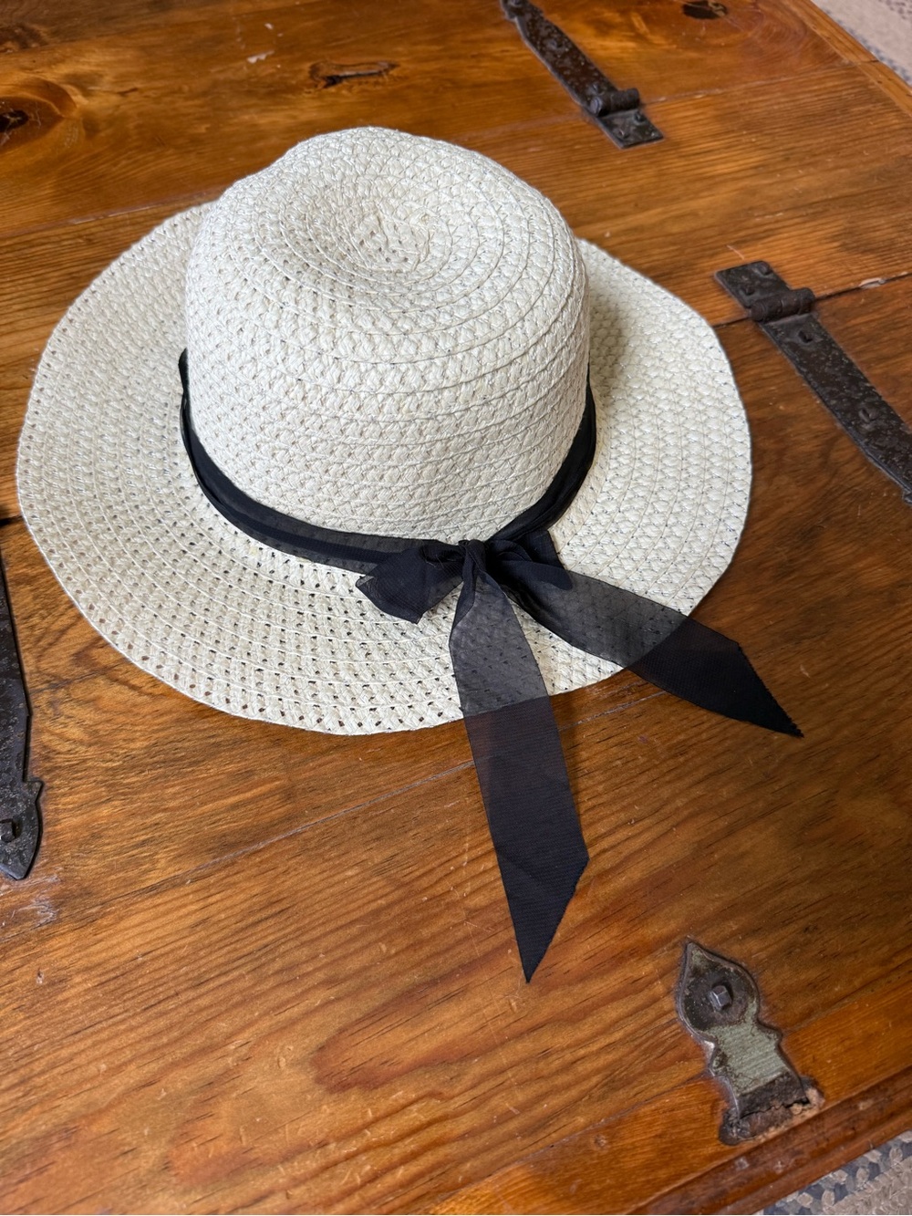 A CALLARON straw sun hat features a lightweight woven design and a black ribbon